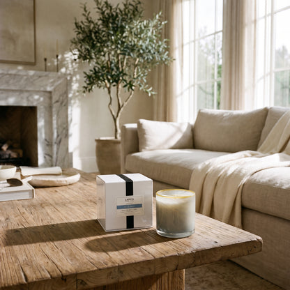 A serene, minimalist living room featuring a rustic wooden coffee table, a neutral sofa, and a LAFCO candle.